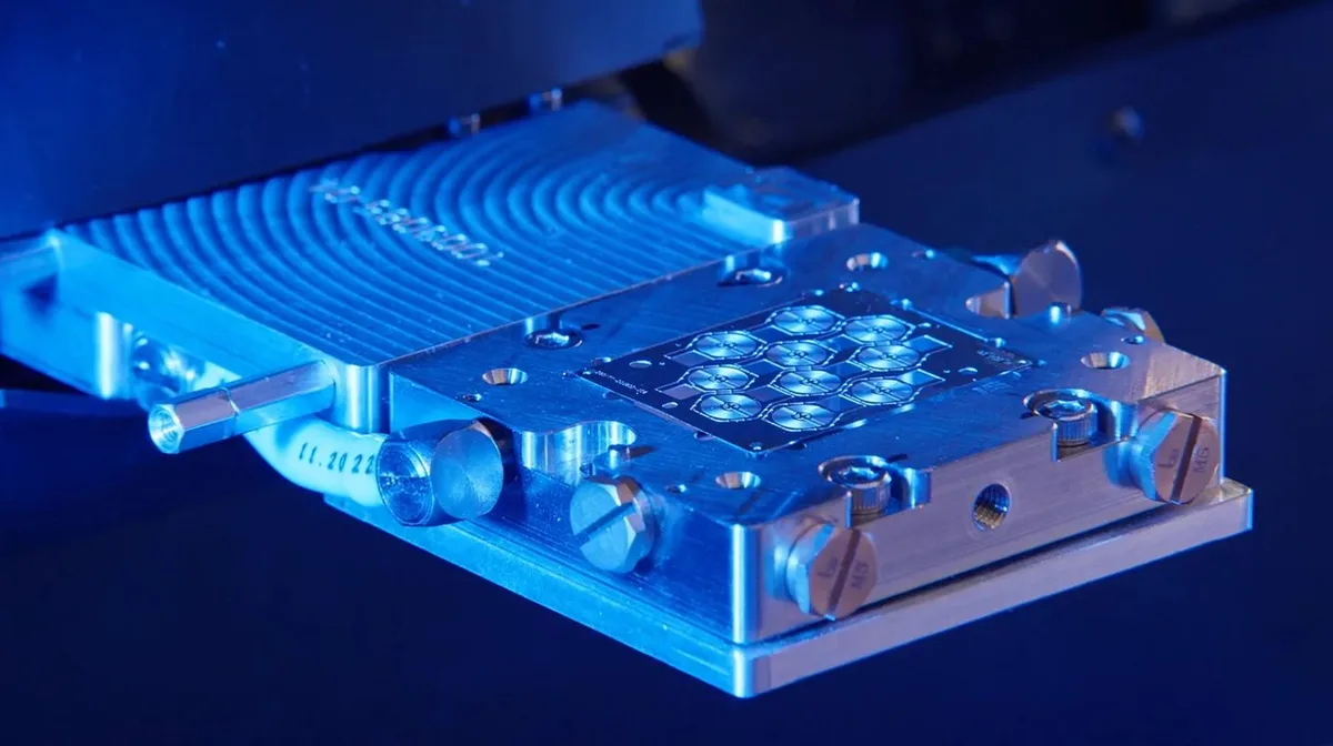 An Atomic Machines device photographed under blue light, a fingertip scale machine built from a digital design