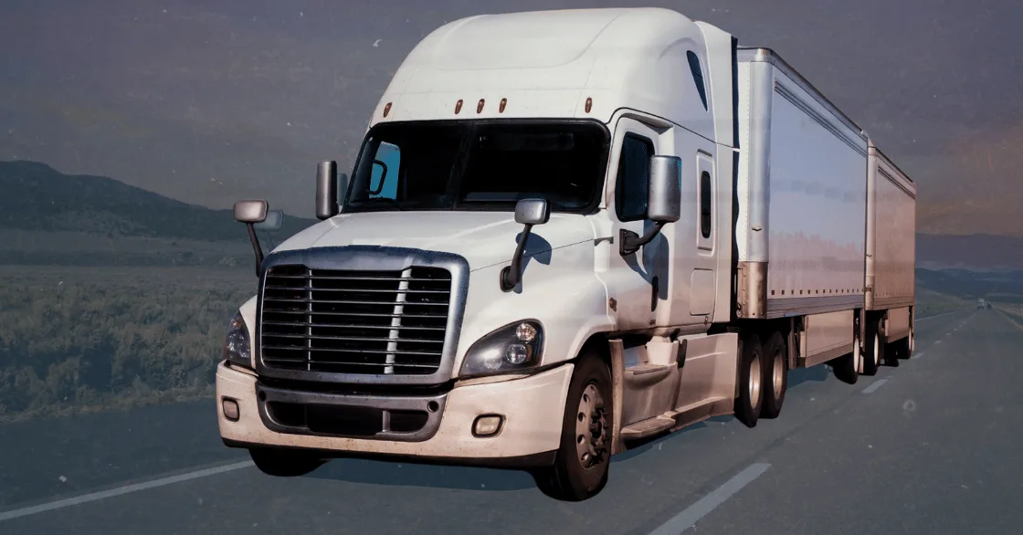 A white semi truck driving on a highway at dusk