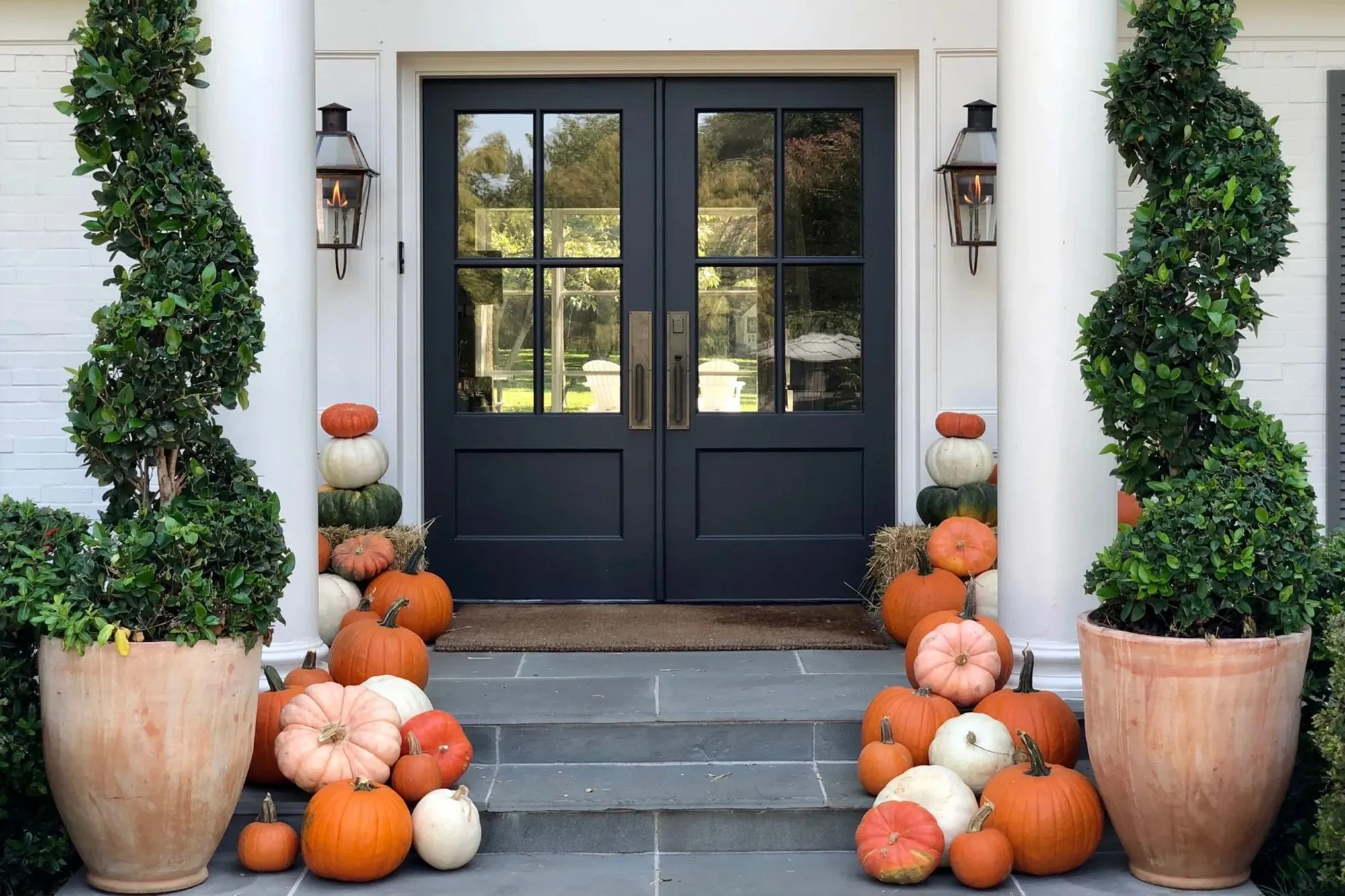 Front steps of a home decorated with pumpkins and fall arrangements by a porch styling service