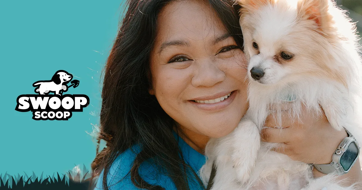 A smiling woman holding a small fluffy white dog outdoors beside the Swoop Scoop logo on a teal background